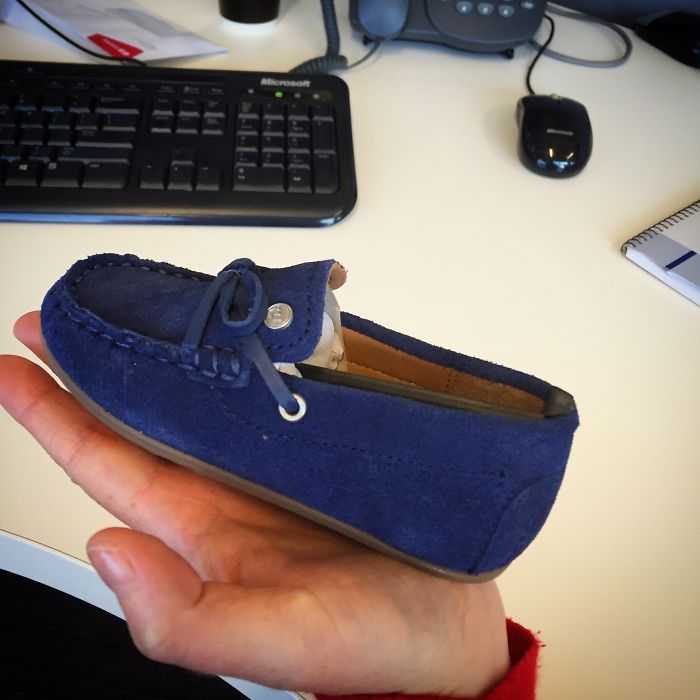 A person holding a tiny blue shoe, illustrating online purchase regret.