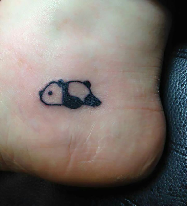 Small foot tattoo of a minimalist panda design showcasing the idea that less is more in tattoo art.