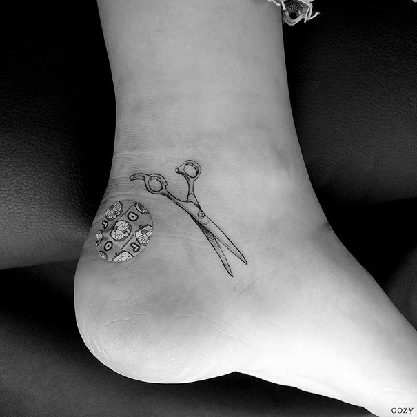 Small foot tattoo featuring scissors and a bandage, showcasing minimalist design.