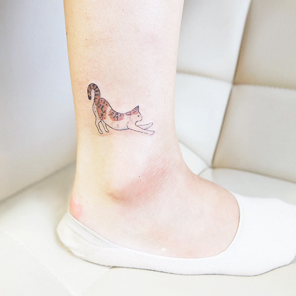 Small foot tattoo of a stretching cat in a minimalist style.