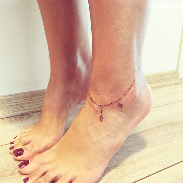 Minimalist small foot tattoo resembling an anklet with delicate geometric designs.