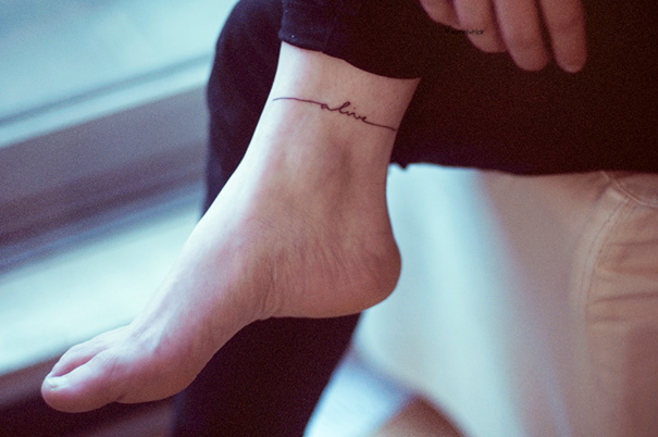 Minimalist small foot tattoo with a delicate script design.