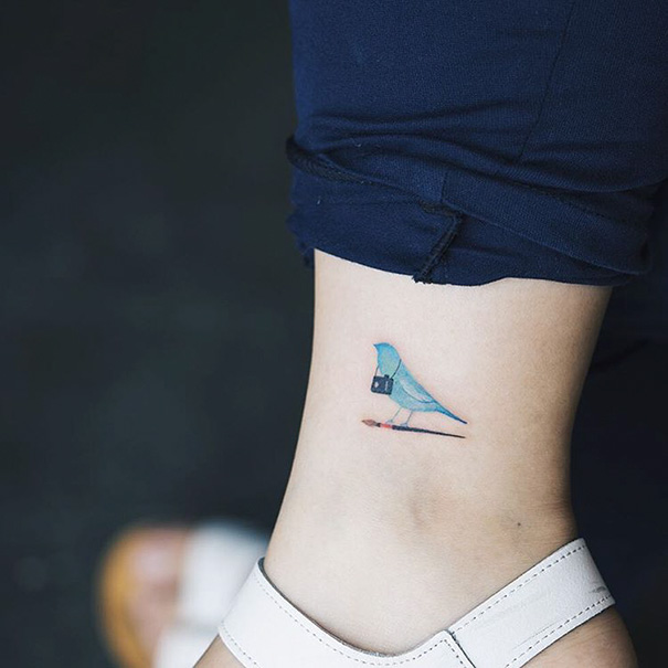 Small foot tattoo of a blue bird on ankle, showcasing minimalist design.