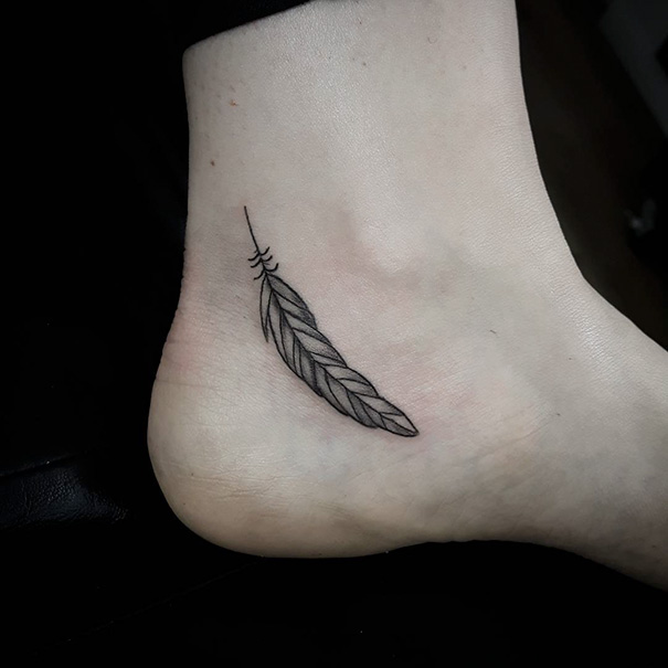 Small foot tattoo of a delicate feather, showcasing minimalist design.