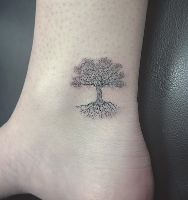 Small foot tattoo of a tree with roots, illustrating minimalist design.