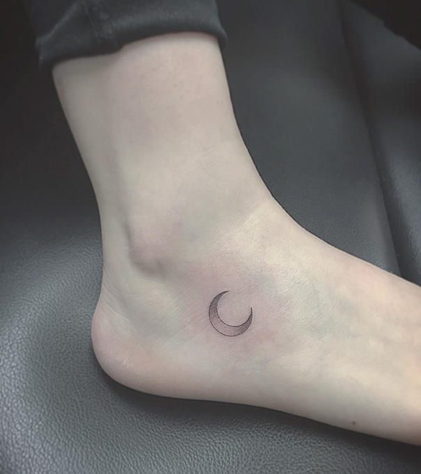 Minimalist small foot tattoo featuring a crescent moon design.