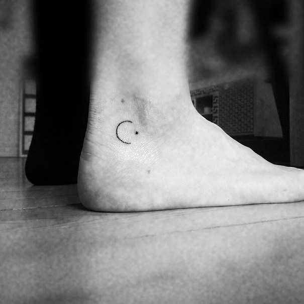 Minimalist small foot tattoo of a crescent moon, symbolizing simplicity and elegance.