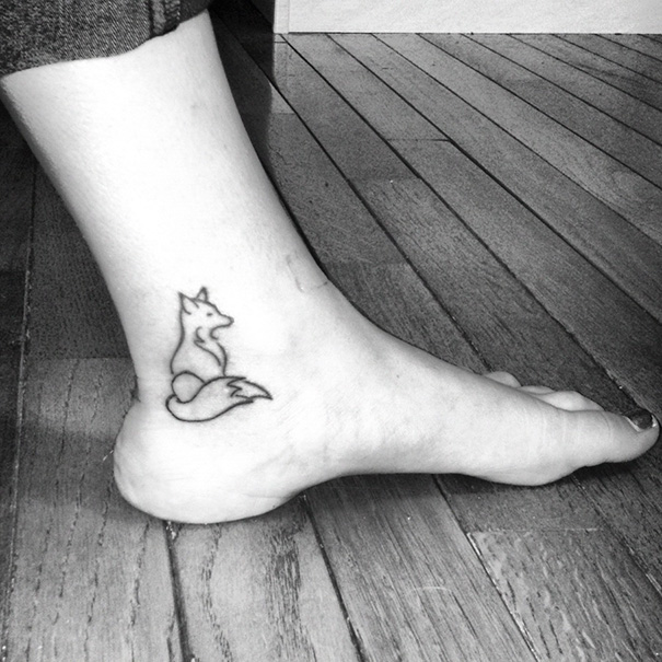 Small foot tattoo of a minimalist fox design on the side of an ankle.