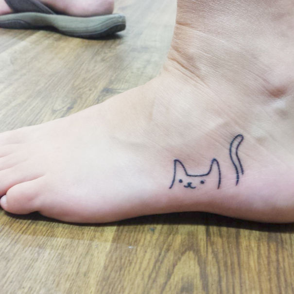 Small foot tattoo featuring a minimalist cat design, highlighting the concept of "less is more" in tattoo art.