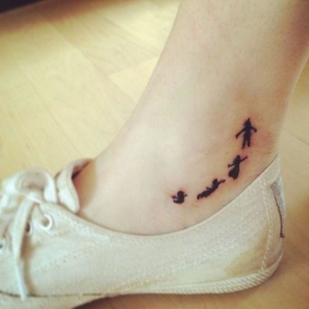 Minimalist small foot tattoo featuring silhouetted figures above a white sneaker, highlighting the less is more concept.