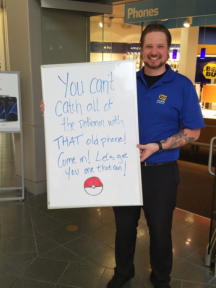 Store employee holding a sign about upgrading phones to catch Pokemon, leveraging the Pokemon Go craze.