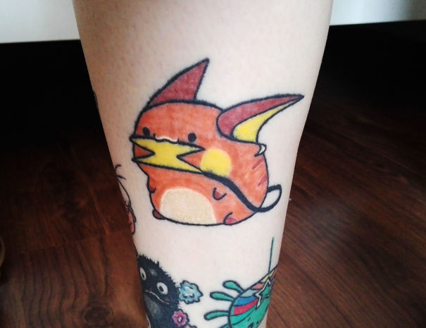 Colorful Pokemon tattoo featuring a chubby, orange character with pointy ears on a person's leg, perfect for fans.
