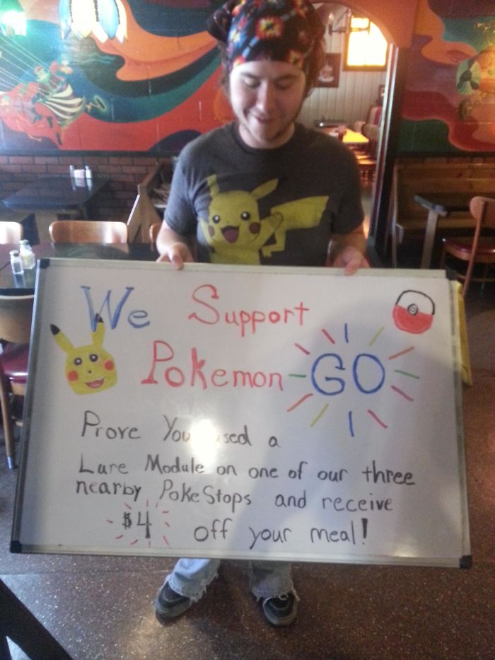 Person holding a sign offering discounts for using a Lure Module in Pokemon Go at local PokeStops.