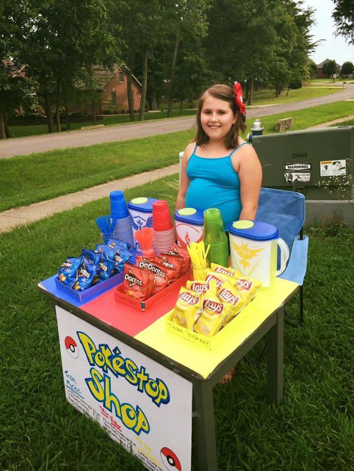 Young girl at a Pokéstop shop stand with snacks and drinks, tapping into the Pokemon Go craze.