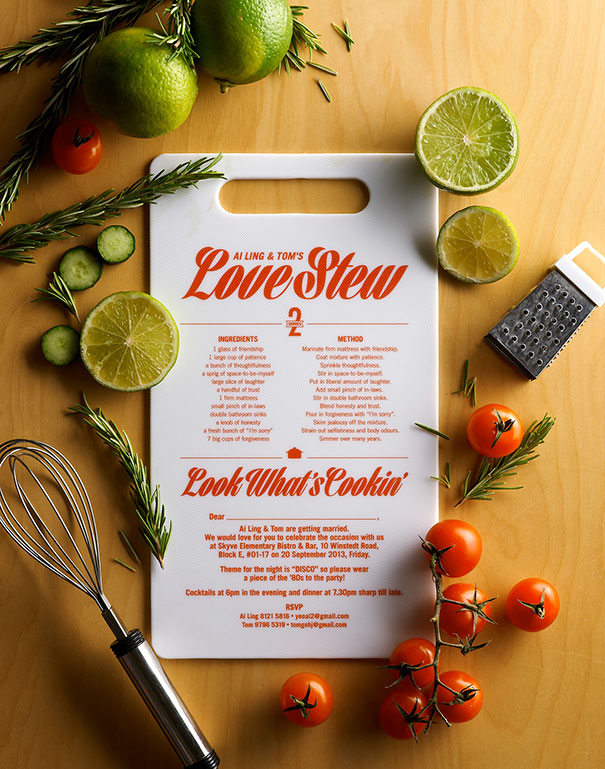 Creative wedding invitation styled as a recipe card surrounded by fresh ingredients and cooking tools on a wooden surface.