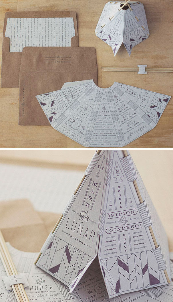Creative wedding invitations with unique foldable design and detailed typography, paired with brown kraft envelopes on a wooden surface.
