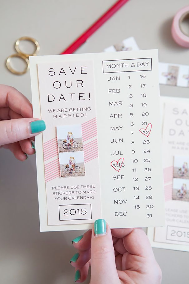 Hand holding creative wedding invitation with save the date and calendar dates marked by heart stickers.