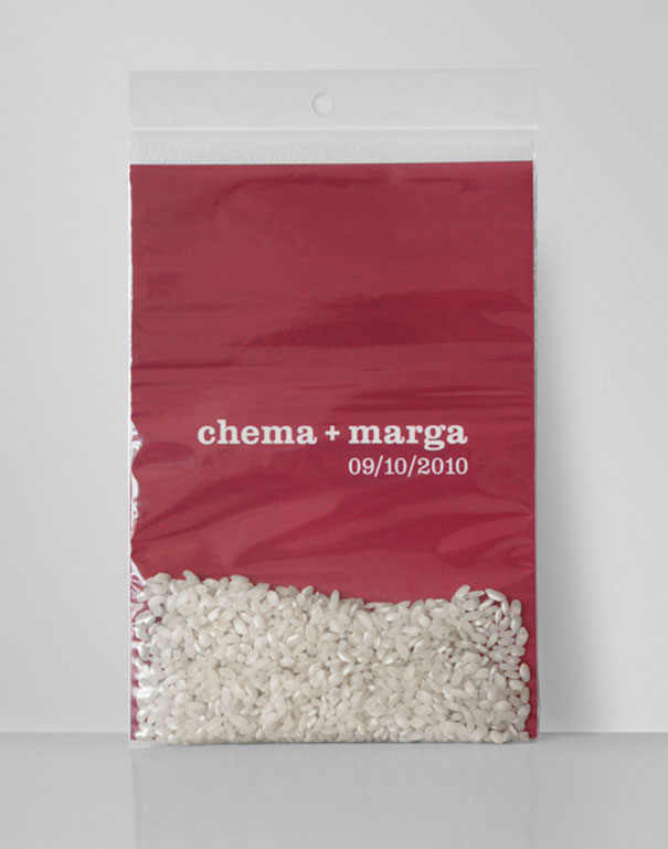 Creative wedding invitation in a clear bag with red backing, personalized names and date, filled with white rice grains.