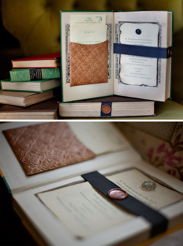 Creative wedding invitations displayed inside vintage books with embossed leather pockets and wax seal embellishments.