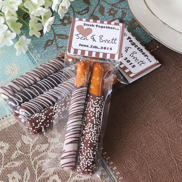 Chocolate-covered pretzel wedding invitations wrapped with personalized tags for a creative and memorable wedding invitation idea.