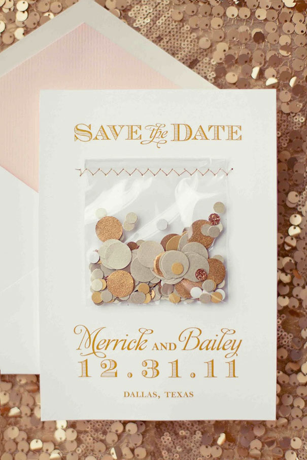 Save the date creative wedding invitation with gold and beige confetti in a clear pouch on white card background.