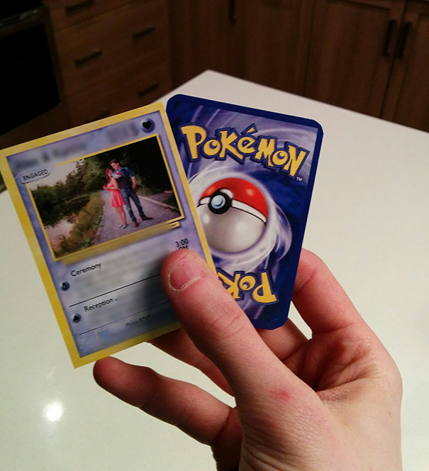 Hand holding creative wedding invitations styled like Pokémon cards featuring engagement details and photo.
