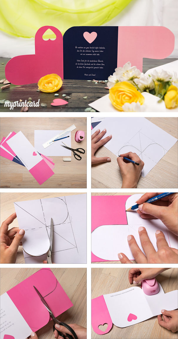 Creative wedding invitations being designed and crafted with pink and navy paper, scissors, and heart shapes on a wooden table.