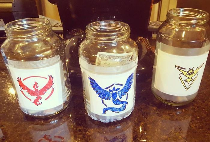 Three jars labeled with Pokemon Go team logos used for tip collection on a countertop.