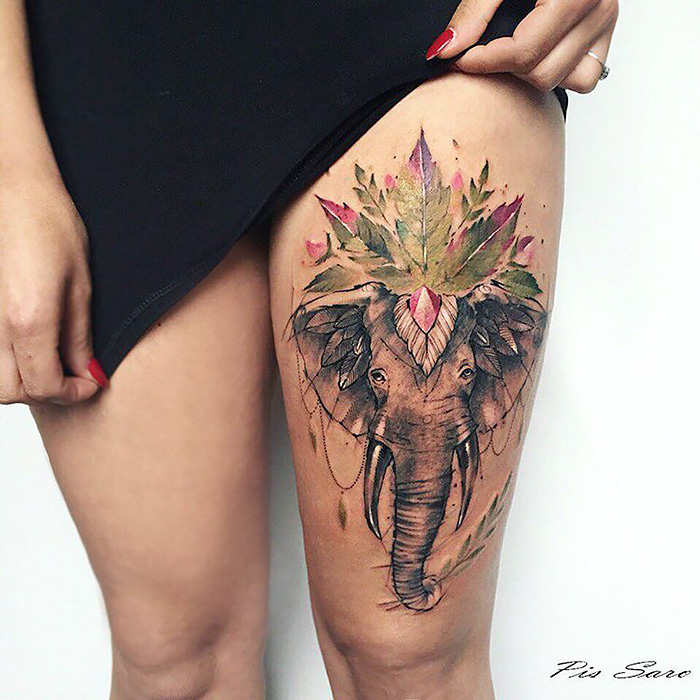 Thigh tattoo depicting an elephant with nature-inspired elements, emphasizing ethereal designs.