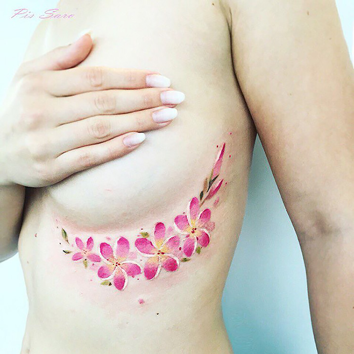 Ethereal nature tattoo of pink flowers along the side of a person's ribcage, symbolizing the changing seasons.
