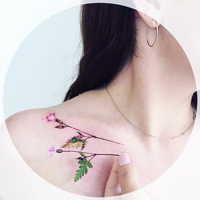Nature tattoo on a shoulder featuring seasonal flowers and leaves.