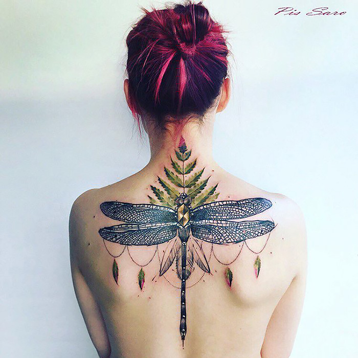 Woman with a large ethereal nature tattoo of a dragonfly and leaves on her back, inspired by changing seasons.