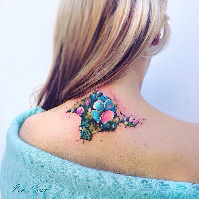 Colorful nature tattoo depicting flowers and leaves on a woman's shoulder, inspired by changing seasons.