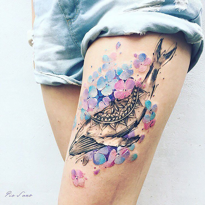 Thigh tattoo of a whale with colorful flowers, inspired by ethereal nature themes and changing seasons.