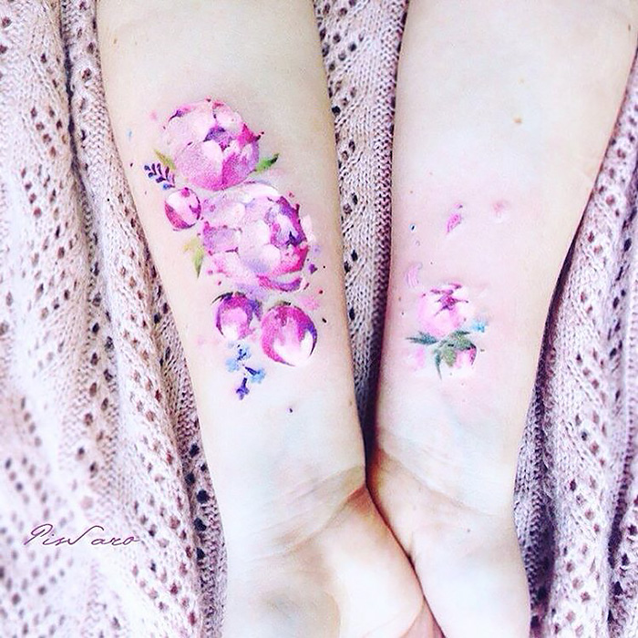 Ethereal nature tattoos with pink floral designs on forearms, inspired by the changing seasons.