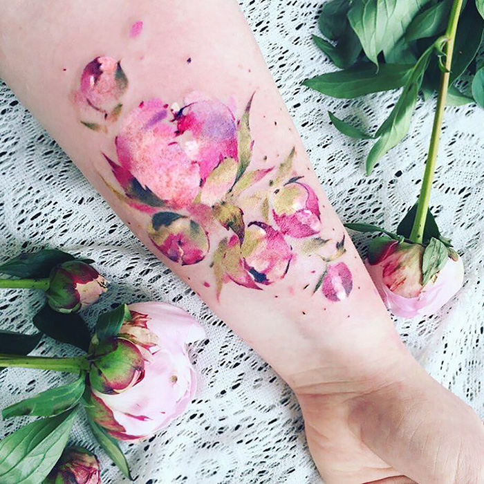 Watercolor floral tattoo on forearm, inspired by nature and changing seasons.