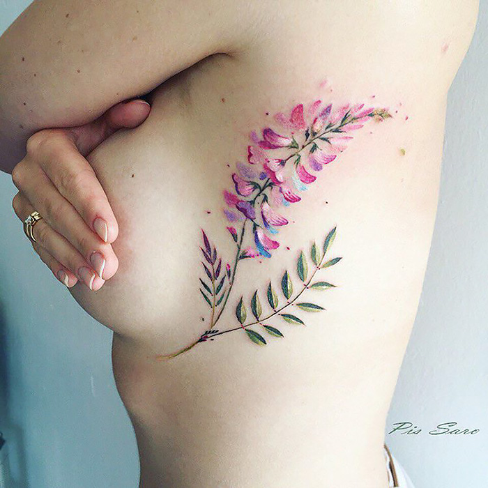 Ethereal nature tattoo on skin, depicting delicate purple flowers and green leaves.