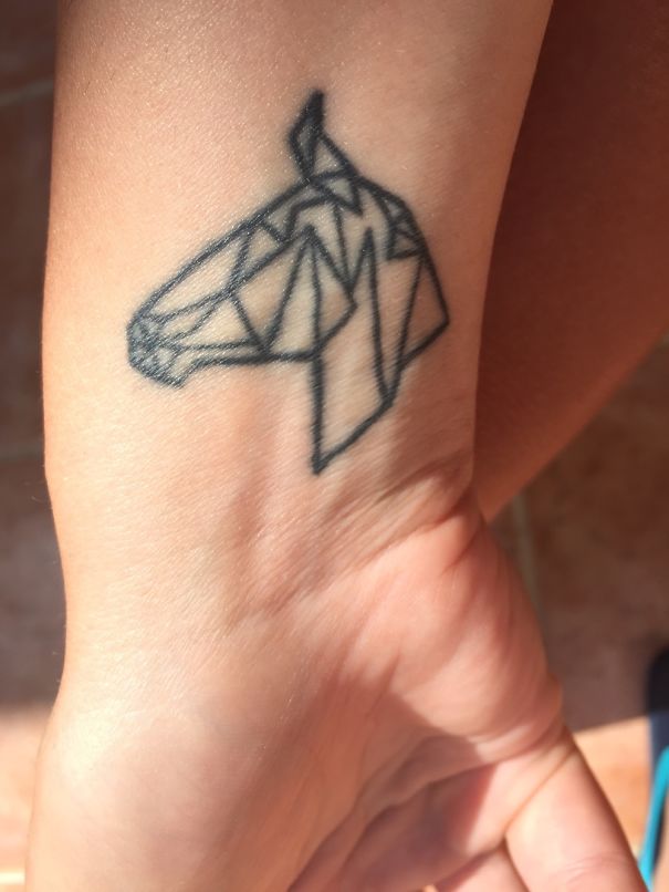 Origami-style geometric horse tattoo on a wrist, inspired by Pixar art.