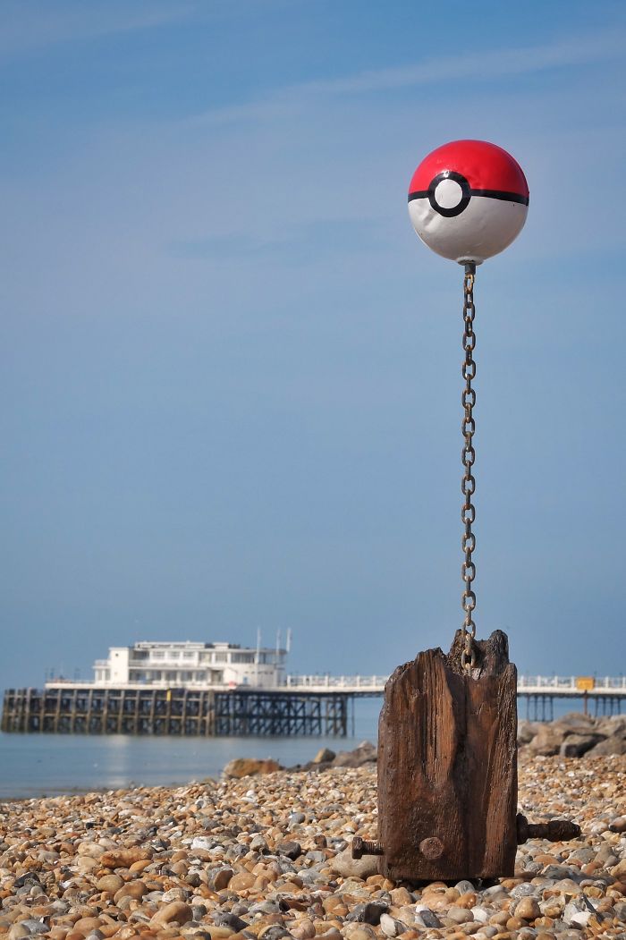 Pokeball display on the beach, highlighting the Pokemon Go craze near a seaside pier.