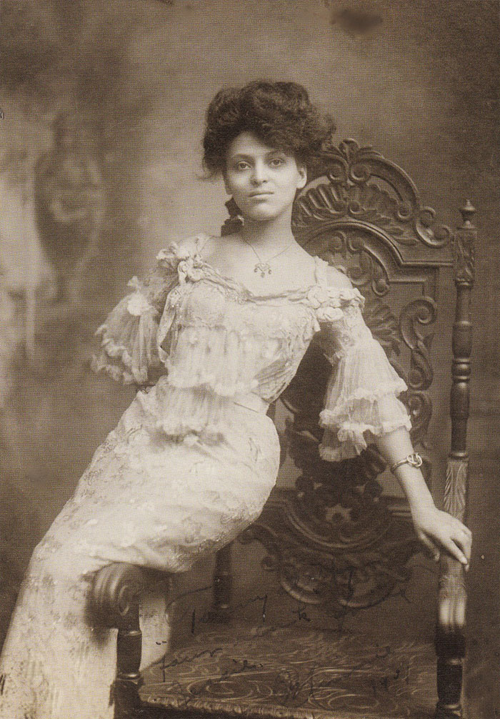 Edwardian era woman in an elegant lace dress, seated on an ornate chair, showcasing early 1900s beauty ideals.