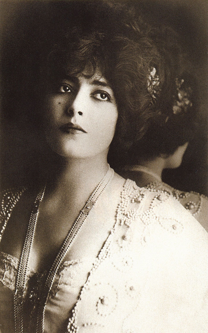 Edwardian era woman with voluminous hair, wearing an ornate dress, showcasing early 1900s beauty style.