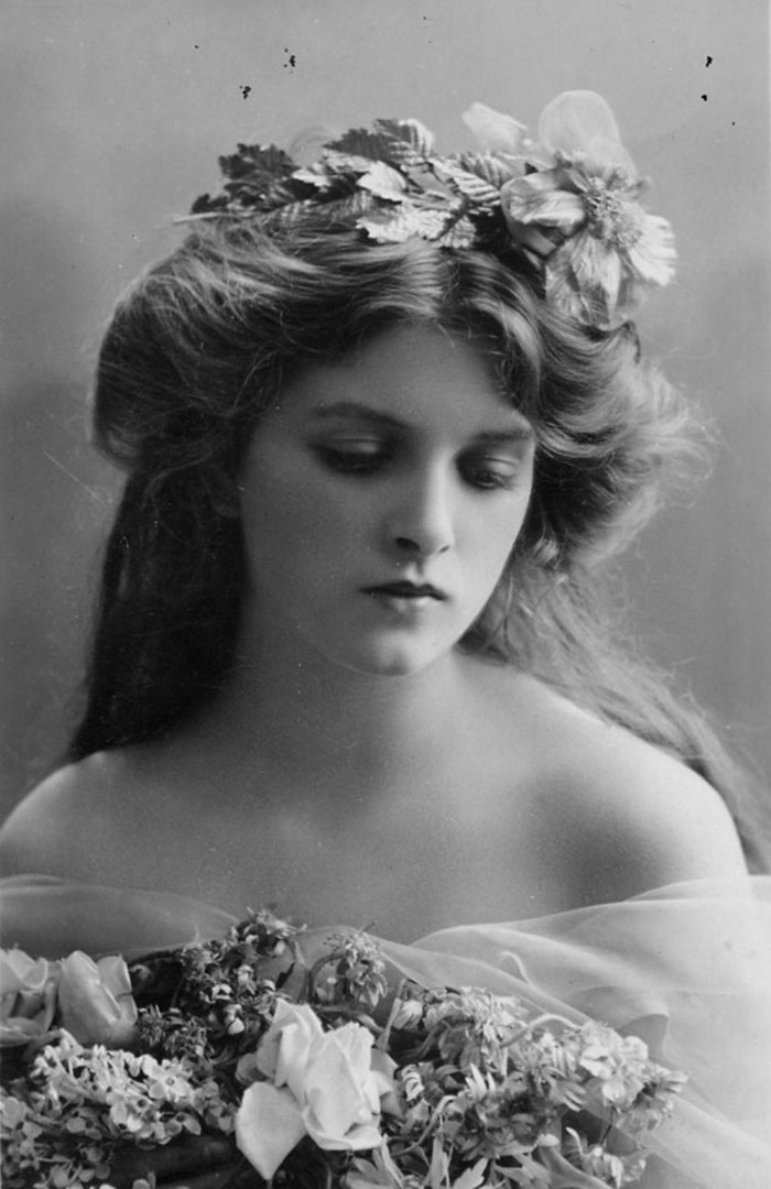 Edwardian era woman with floral crown and bouquet, showcasing early 1900s beauty.