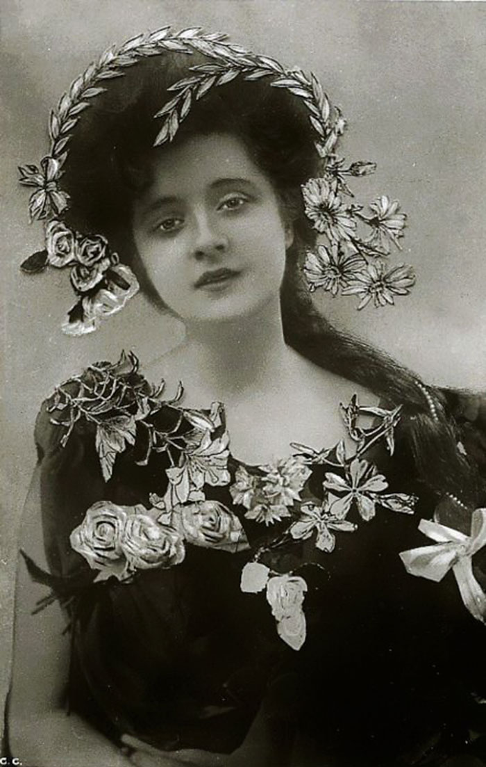 Edwardian era woman with floral decor in her hair and dress, representing timeless beauty.