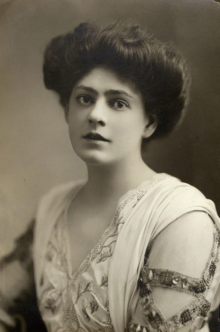 Edwardian era woman with intricate hairstyle and embroidered dress, embodying early 1900s beauty.