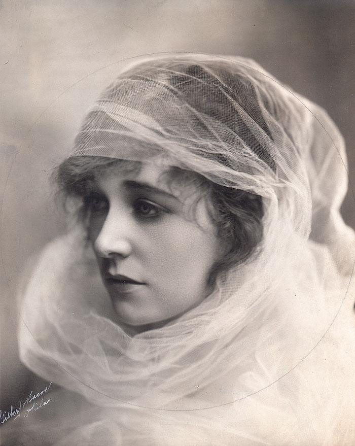 Edwardian woman draped in a sheer veil, representing early 1900s beauty.