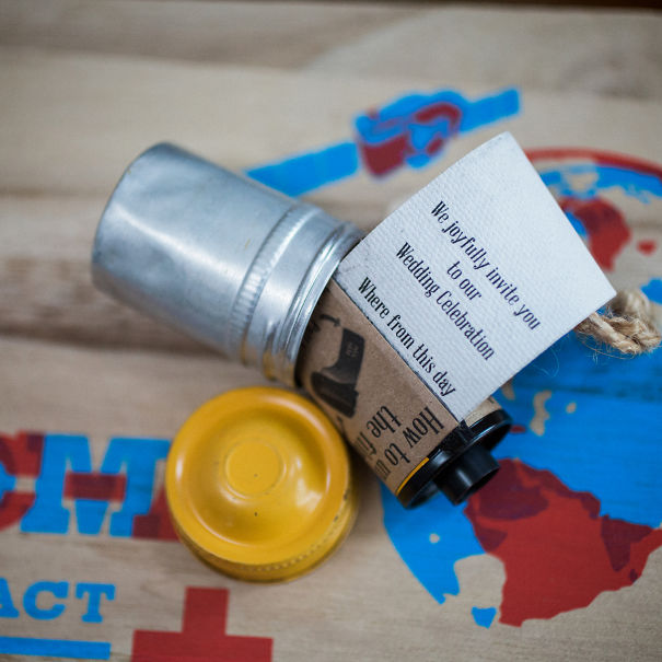 Vintage film roll with a creative wedding invitation scroll inside, showcasing unique and artistic wedding invitation ideas.