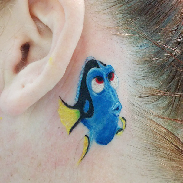Pixar tattoo featuring a colorful fish character inked behind someone's ear.