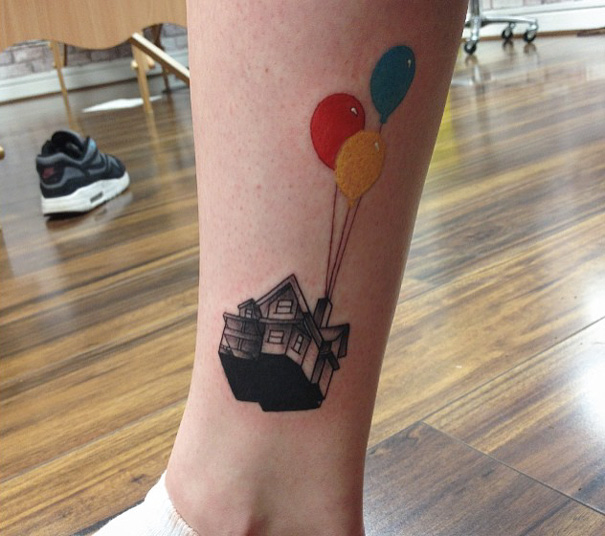 Pixar-inspired tattoo of a house with colorful balloons on a person's leg.
