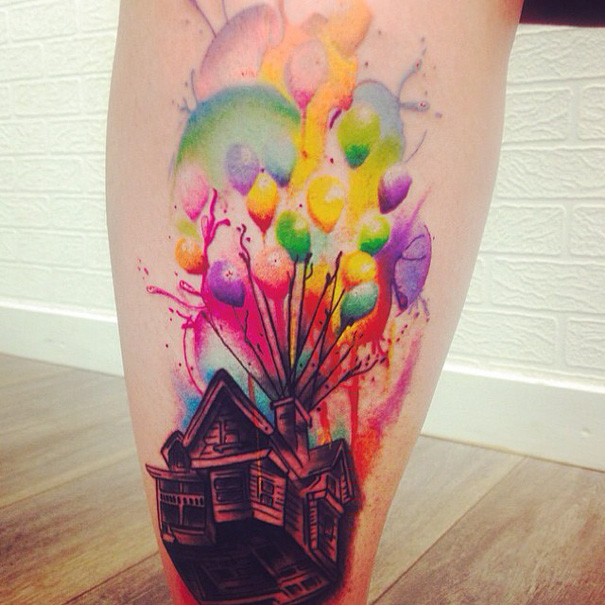 Colorful Pixar-inspired tattoo of a house lifted by balloons on a leg.