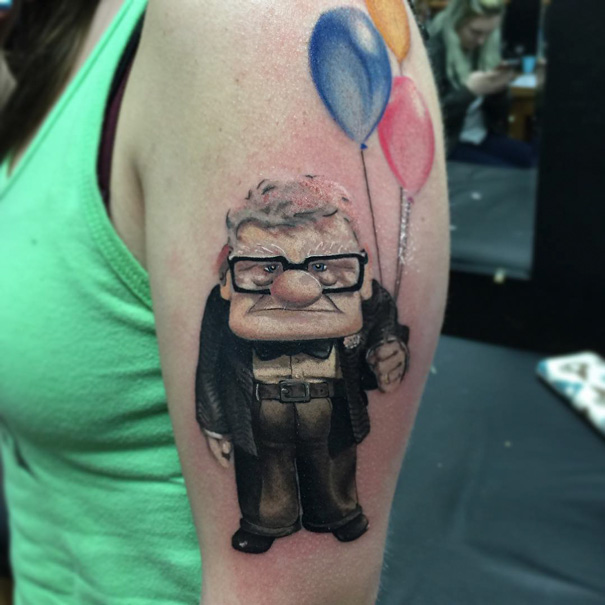 Pixar-inspired tattoo of an elderly man holding colorful balloons on the upper arm, showcasing detailed design.